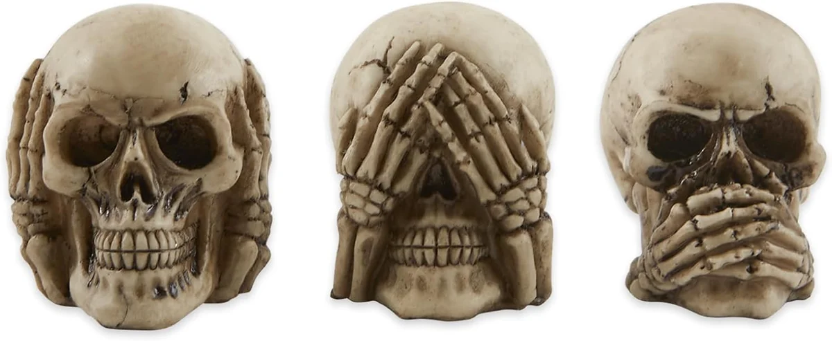 Set of three small resin human skull figurines posed as the see no evil, hear no evil, speak no evil trio, each covering its eyes, ears, or mouth with bony hands, finished in an aged bone-white color for shelf or desk display